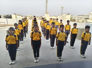 Students in yellow uniforms standing in straight rows on the terrace during school assembly, reflecting discipline, coordination and teamwork together
