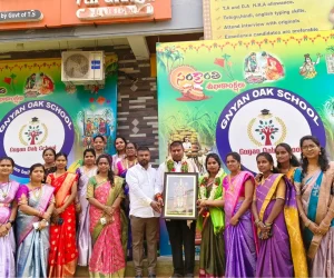 Group of staff members standing outside the school building holding a framed picture and smiling together as a dedicated faculty team.