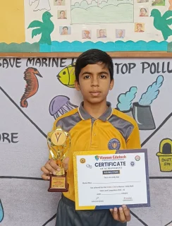 Gnyan Oak School student in yellow uniform holding trophy and certificate standing in front of wall with Republic Day drawings