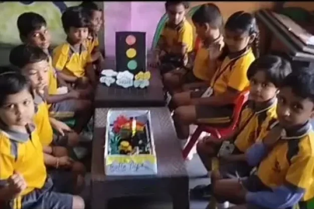 Students sitting around a table with traffic light model and learning materials in classroom at Gnyan Oak School during practical activity.